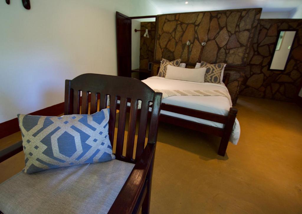 a bedroom with a bed and a bench with a pillow at Kiambi Safaris Lodge in Chiawa