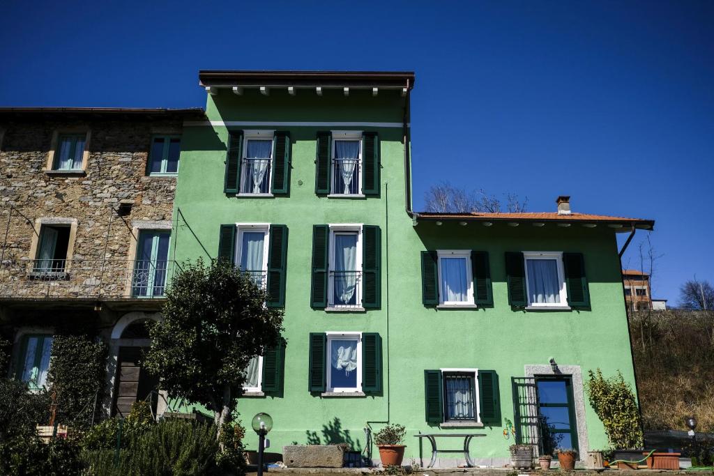 a green building with white windows and a blue sky at Teresita-the Green House in Pisano