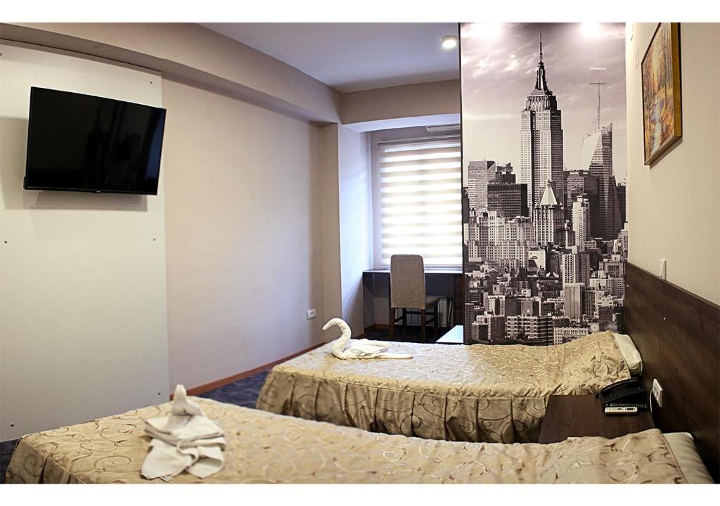 a hotel room with two beds and a wall mural of a city at Hotel Ambasador in Skopje