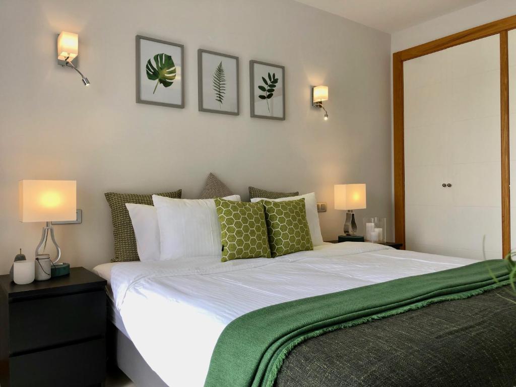 1 dormitorio con 1 cama blanca grande con almohadas verdes en Vista Golf 15, en La Playa de Arguineguín
