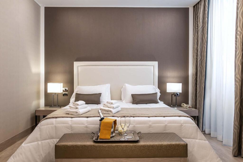 ローマにあるホテル ジェノヴァの大きなベッドとテーブルが備わるホテルルームです。