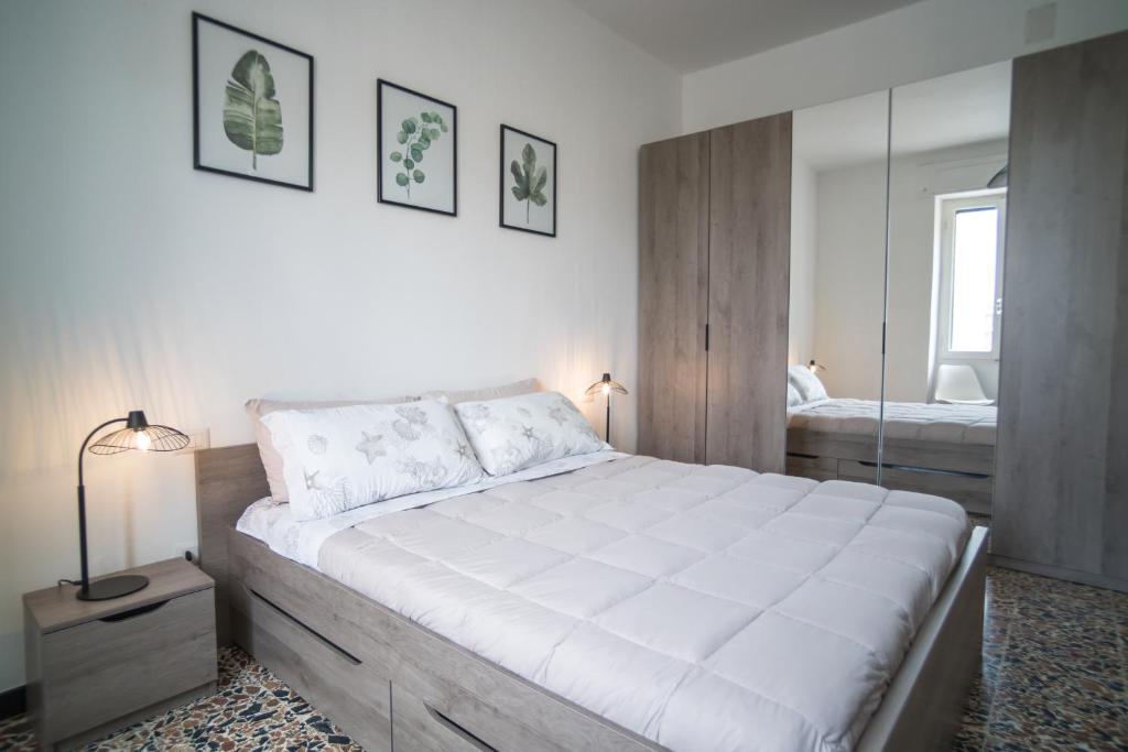 ein Schlafzimmer mit einem großen weißen Bett und einem Spiegel in der Unterkunft Appartamento ClaRa in Alghero