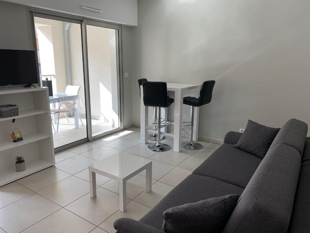 un salon avec un canapé et une table avec des chaises dans l'établissement Studio les pieds dans l'eau Plage du Trottel, à Ajaccio