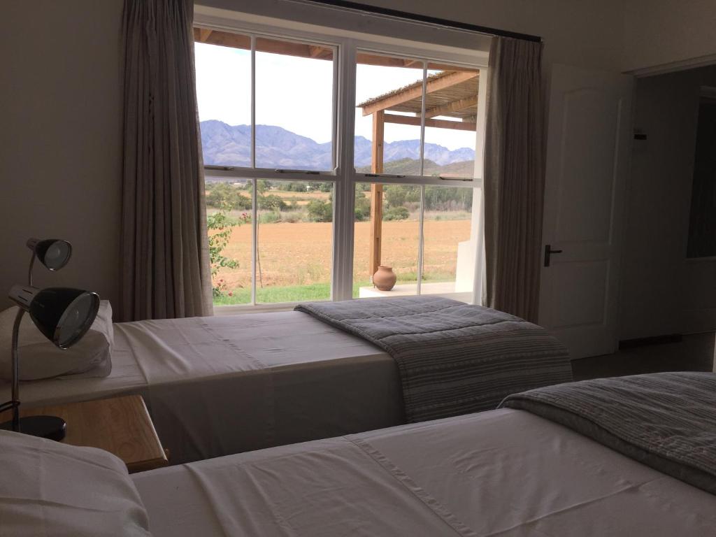 1 dormitorio con 2 camas y ventana grande en Pepper Tree Cottage, en De Rust