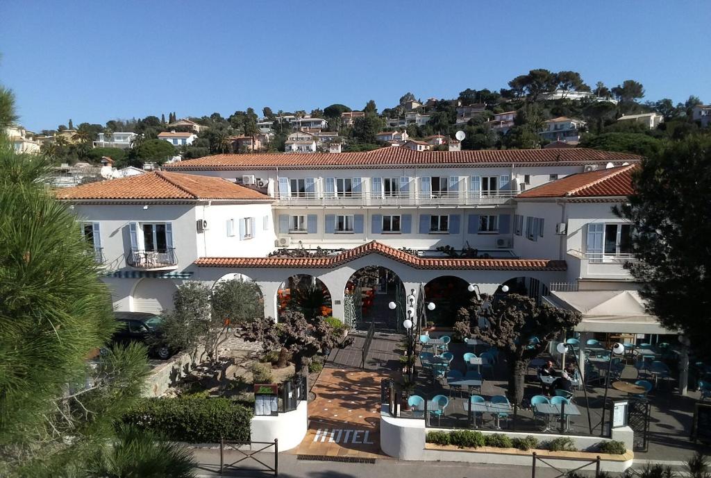 ein großes weißes Gebäude mit einem Restaurant davor in der Unterkunft Logis Hotel Le Provencal in Les Issambres