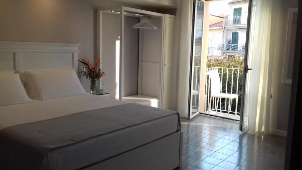 a bedroom with a bed and a balcony with a chair at Residenza Corallina in Tropea
