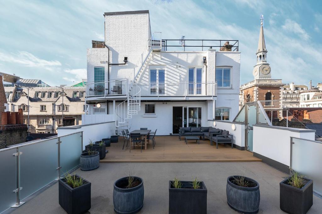 d'un balcon orné de plantes en pot et d'une maison blanche. dans l'établissement JOIVY Luxury 2 bed flats with terraces near Piccadilly Circus, à Londres