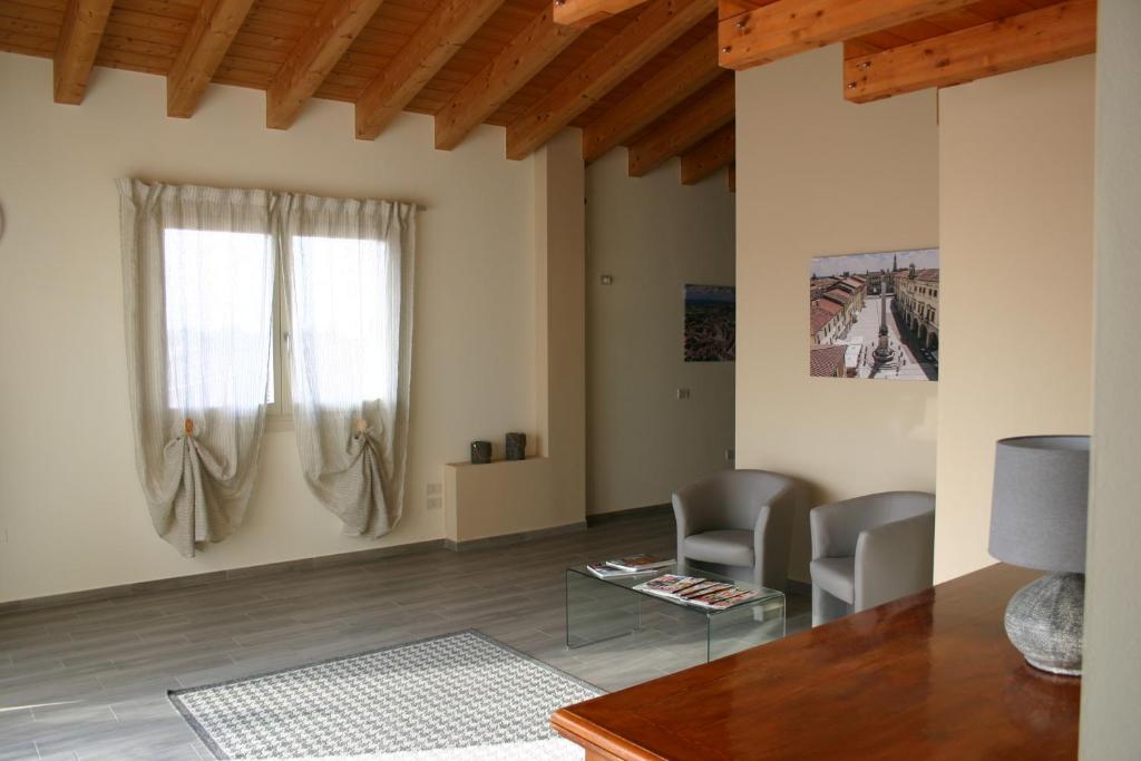 ein Wohnzimmer mit einem Tisch, Stühlen und einem Fenster in der Unterkunft Via Venezia Accomodating Solutions in Lonigo