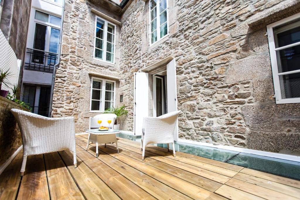 une terrasse en bois avec deux chaises et un bâtiment dans l'établissement Hotel Montenegro Compostela, à Saint-Jacques-de-Compostelle