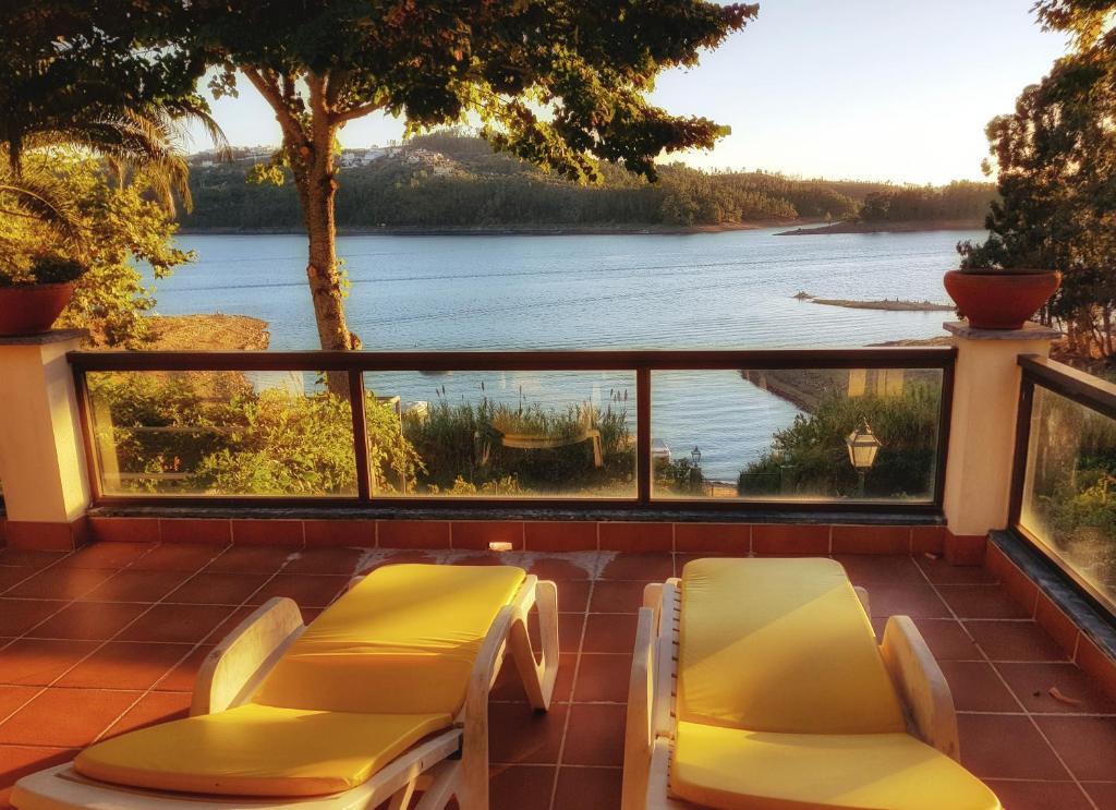 a balcony with two chairs and a view of a lake at Paraíso Azul in Eira do Chão