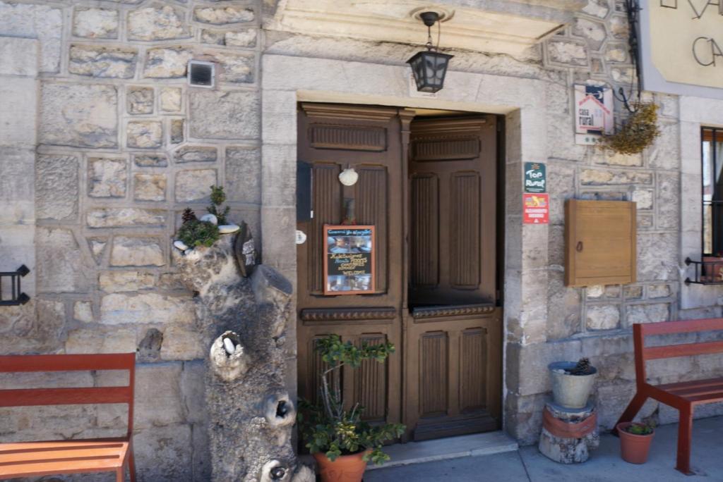 a stone building with a wooden door and a bench at La Alpargateria in Villafranca-Montes de Oca