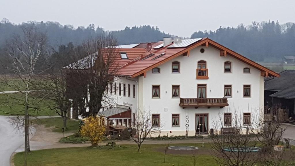 ein großes weißes Haus mit rotem Dach in der Unterkunft Pension Baumgartner in Rott am Inn