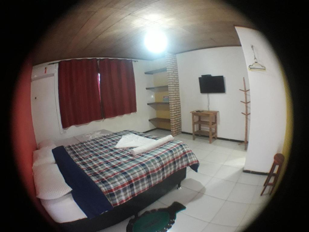 una piccola camera con letto e televisore di Pousada Sena a Flecheiras
