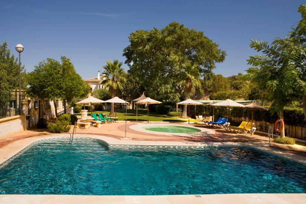 a large swimming pool with chairs and umbrellas at La Cueva Park in Jerez de la Frontera