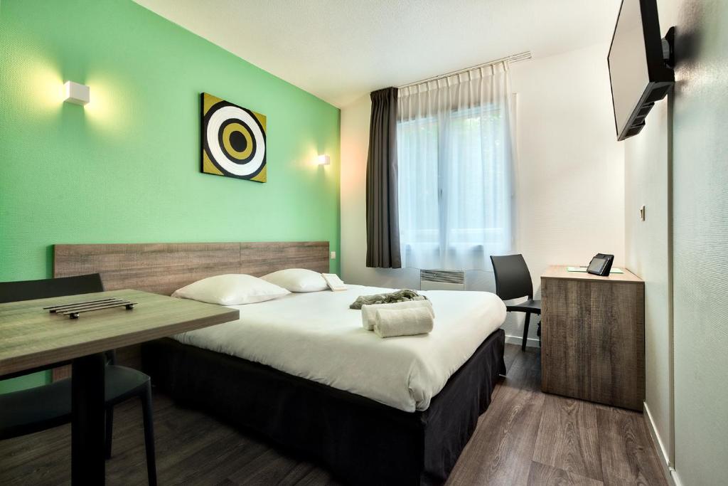 una camera d'albergo con un grande letto e una scrivania di Zenitude Hôtel-Résidences Toulouse Métropole a Tolosa