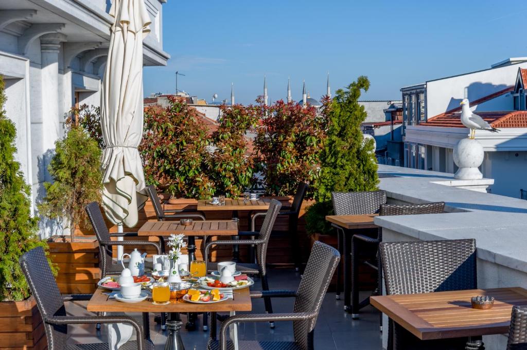 un patio al aire libre con mesas, sillas y una sombrilla en Bizim Hotel, en Estambul