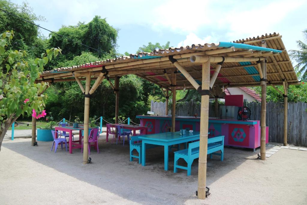 a wooden pergola with tables and chairs under it at Meno Suites in Gili Meno