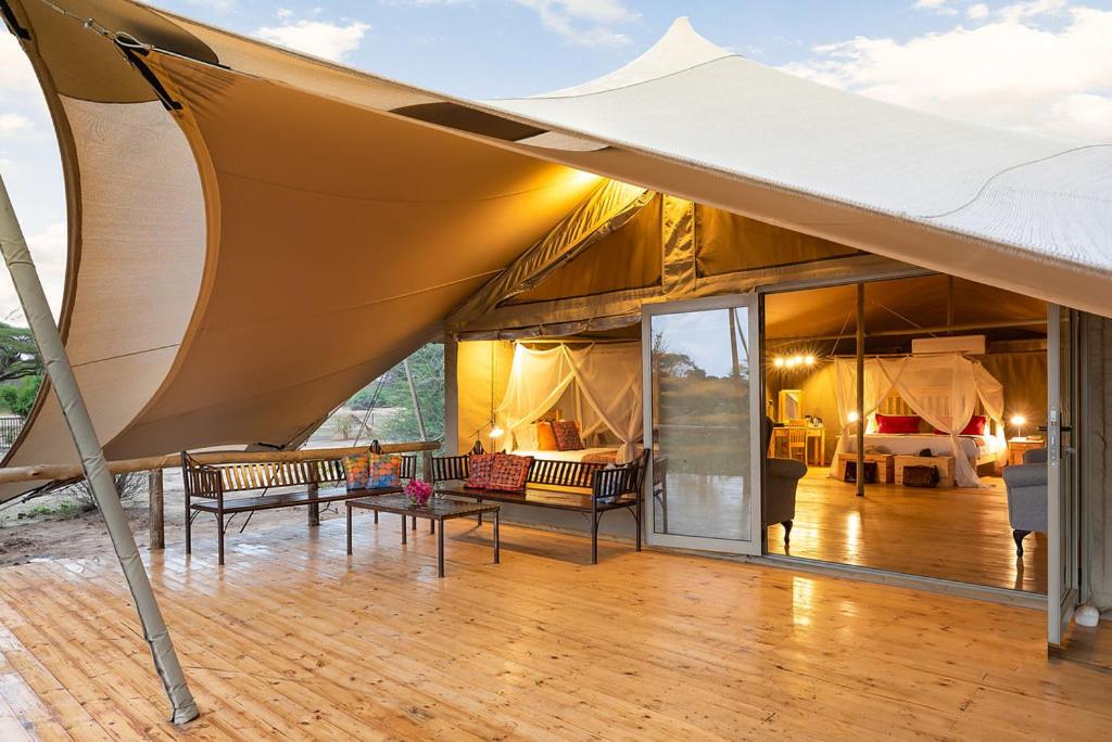 a large tent with chairs and tables on a wooden floor at Tlouwana Camp in Kasane