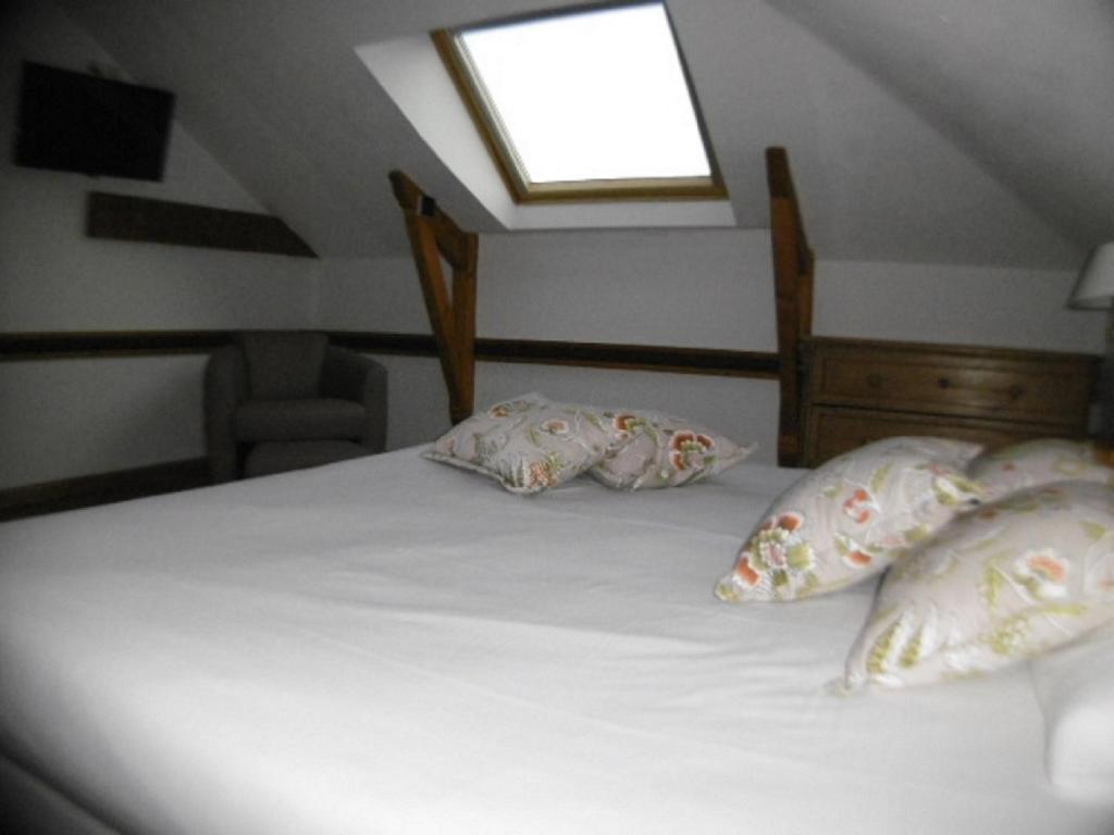 a bedroom with a bed with pillows and a window at Hôtel La Flore in Villefranche-sur-Mer