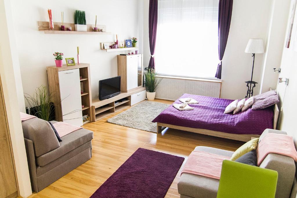sala de estar con cama morada y sofá en Andy's Home Central Apatment, en Budapest