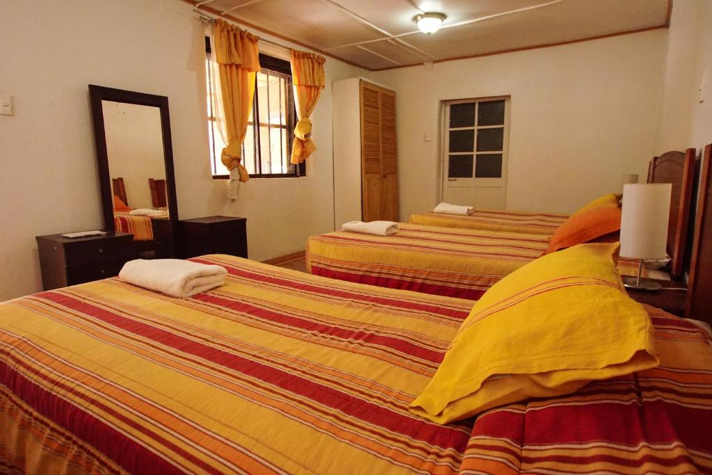 a hotel room with two beds with yellow and orange sheets at Quinta Adela Bed & Breakfast in San Pedro de Atacama