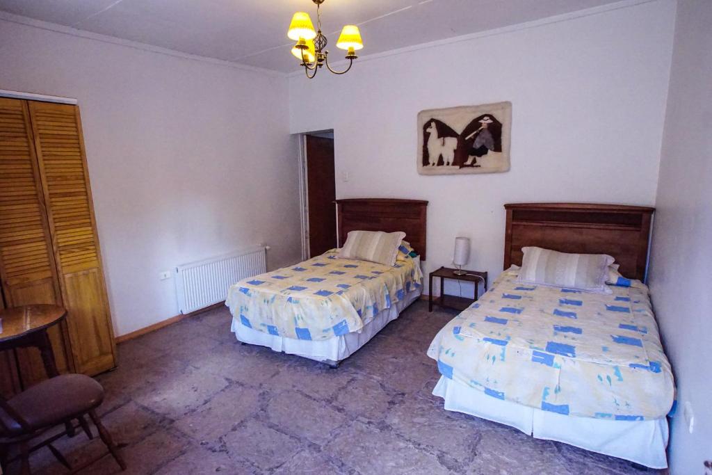 a bedroom with two beds and a table and chairs at Quinta Adela Bed & Breakfast in San Pedro de Atacama