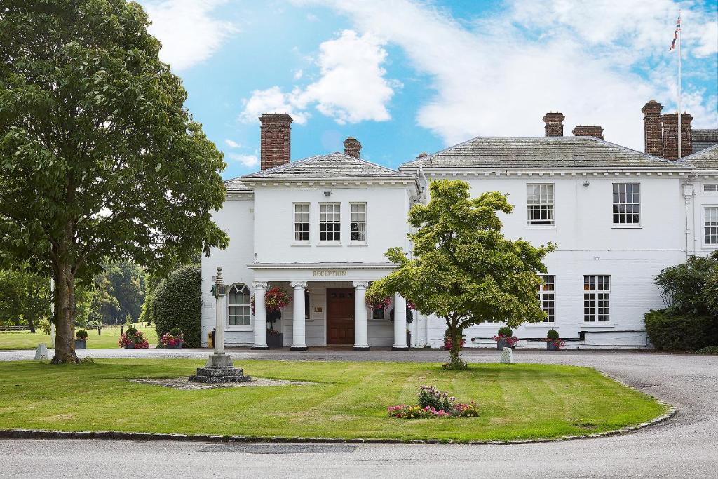 Una casa blanca con un árbol delante. en Milton Hill House en Didcot