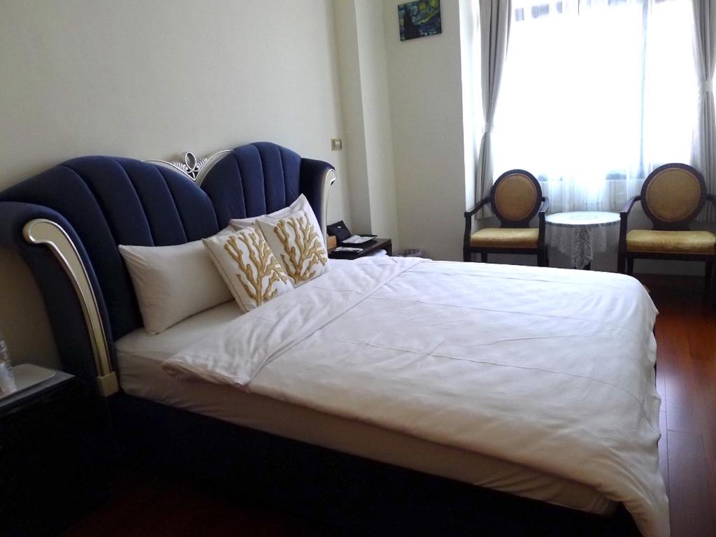 a bedroom with a large bed with a blue headboard at Amicasa Guesthouse in Hualien City