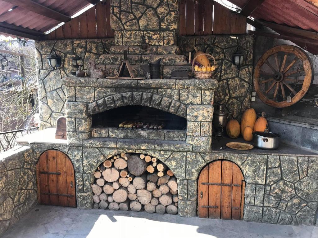 a stone oven with a pile of logs and pumpkins at Guest House Anahit Ijevan in Ijevan