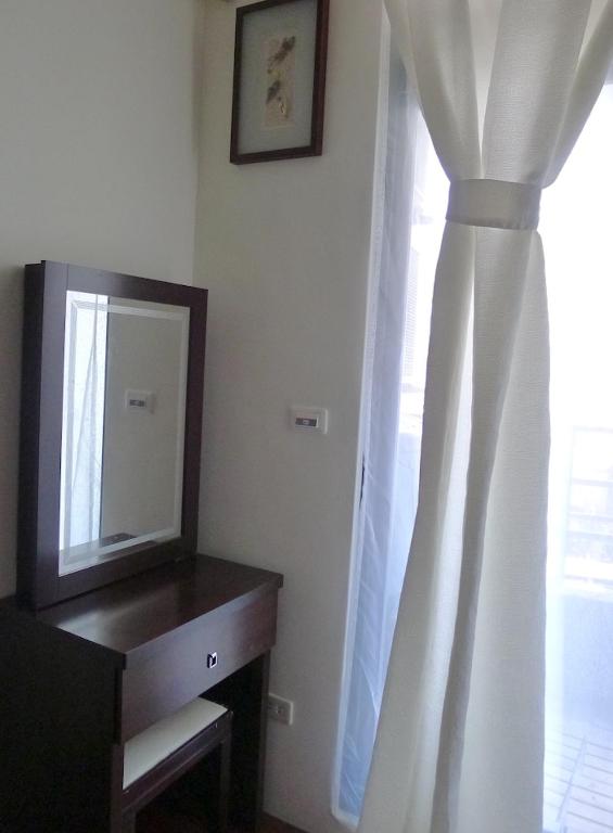 a mirror and a dresser in a room with a window at Amicasa Guesthouse in Hualien City