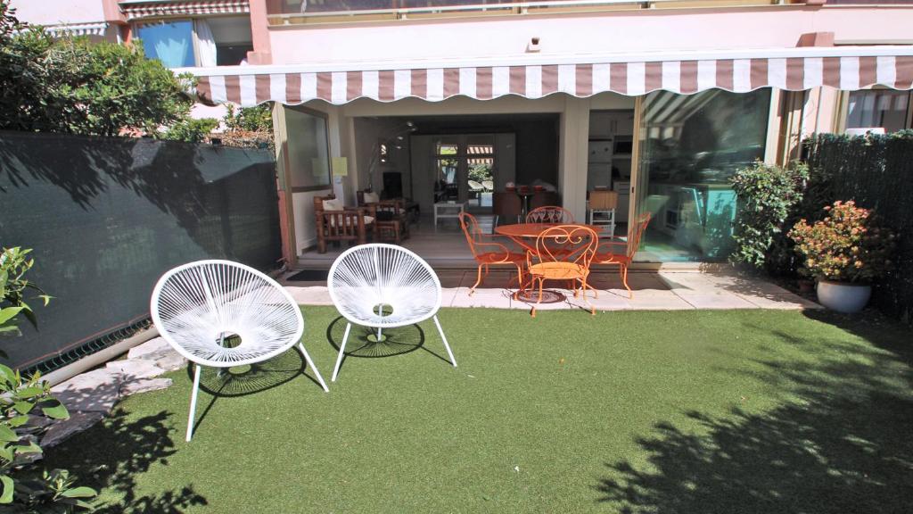 2 chaises blanches et une table dans la cour dans l'établissement Terres Marines, à Sainte-Maxime