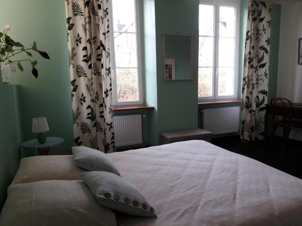 a bedroom with a large white bed with windows at AMBIANCES chambres d 'hôtes in Baye