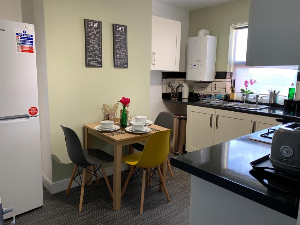 a small kitchen with a small table and chairs at Buccleuch Apartment in Kettering