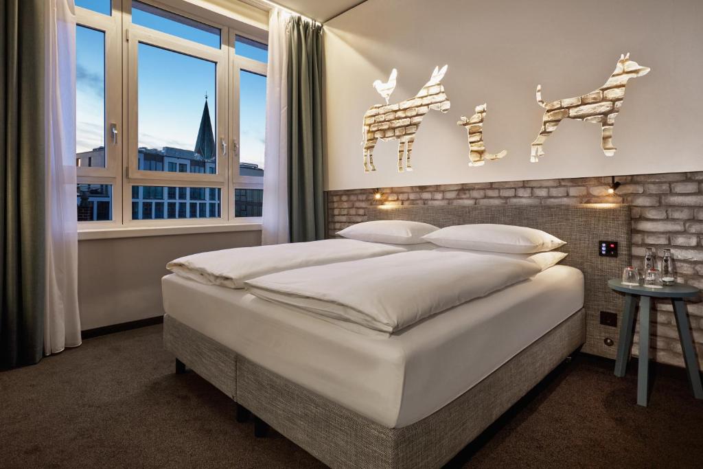 um quarto com uma grande cama branca e uma janela em H+ Hotel Bremen em Bremen