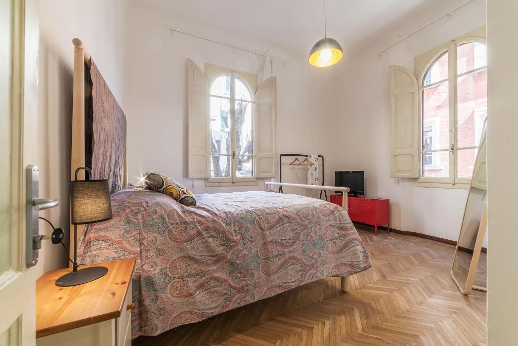 a bedroom with a bed and a desk and two windows at Tilia in Bologna