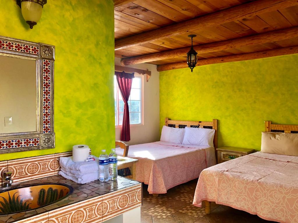 a bedroom with two beds and a mirror and a sink at Hotel JADE in Mesa Colorada