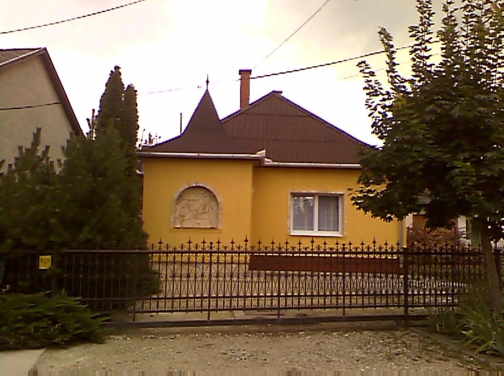 żółty dom z czarnym płotem w obiekcie Apartman Sas 6 w Hajduszoboszlo