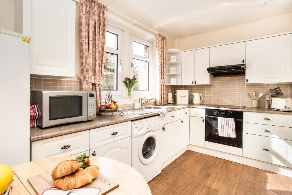 a kitchen with white cabinets and a table at Mabel's View in Melrose