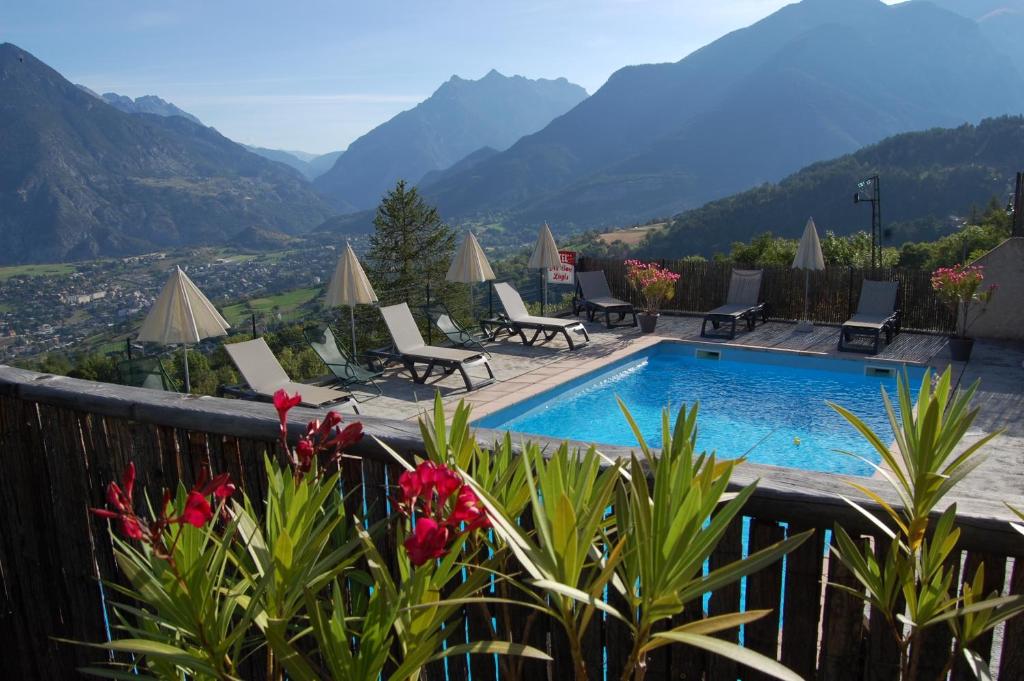 a resort with a pool and mountains in the background at Au Bon Logis in Risoul
