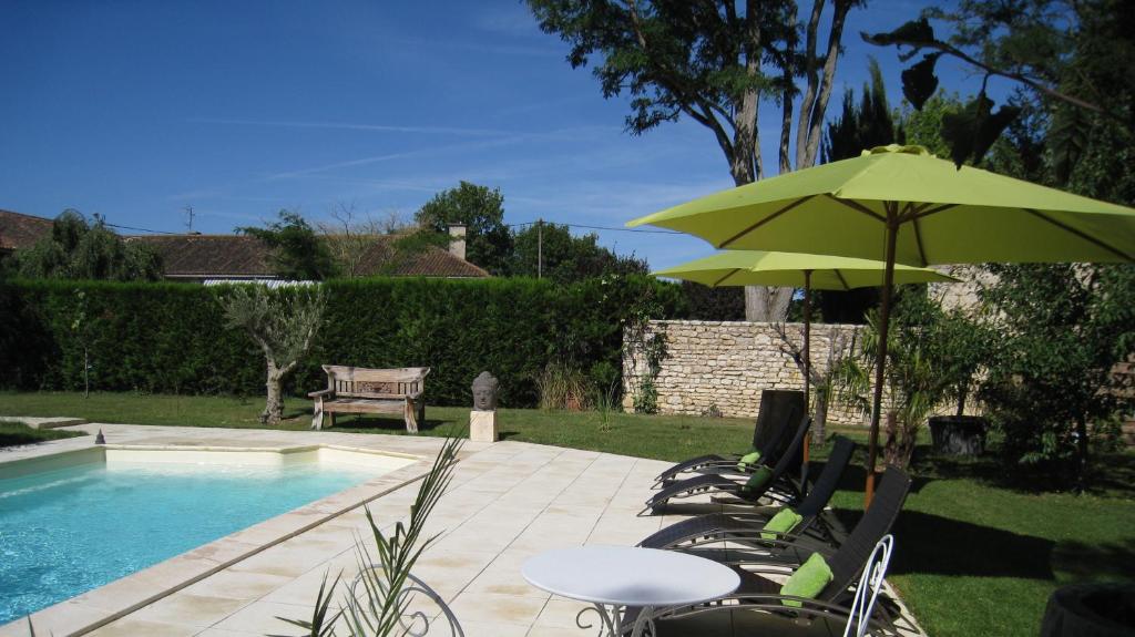 a table and chairs with a green umbrella next to a pool at Le Chai de Villiers in Villiers