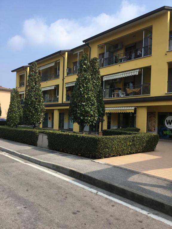 żółty budynek z drzewami przed ulicą w obiekcie appartamento MARGHERITA w Sirmione