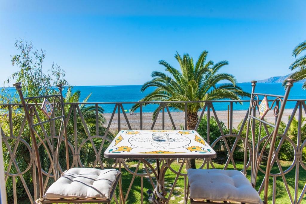 een tafel en stoelen met het strand op de achtergrond bij Hotel Villa delle Palme in Sapri