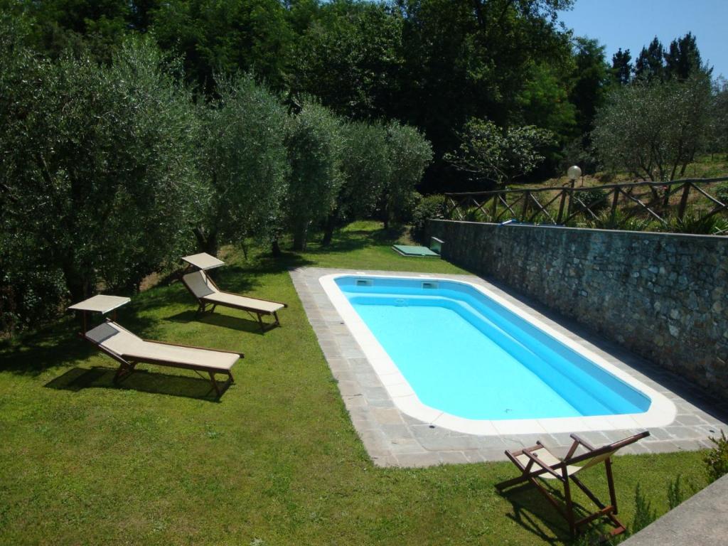 uma piscina com duas espreguiçadeiras e uma piscina em Fattoria Ceragioli em Camaiore