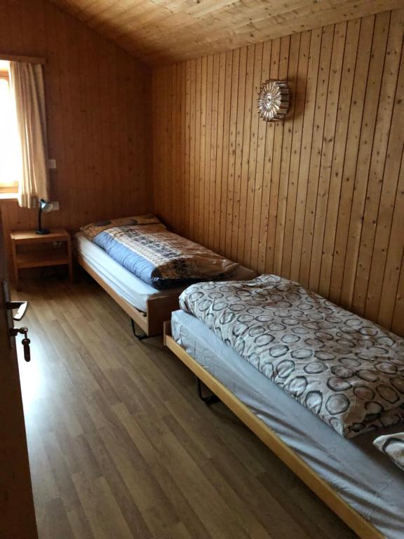 Duas camas num quarto com paredes de madeira em rest bellavista em Maloja