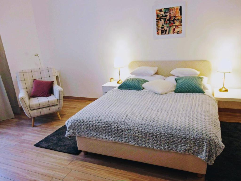 ein Schlafzimmer mit einem großen Bett und einem Stuhl in der Unterkunft Sedaki Apartments in Zagreb