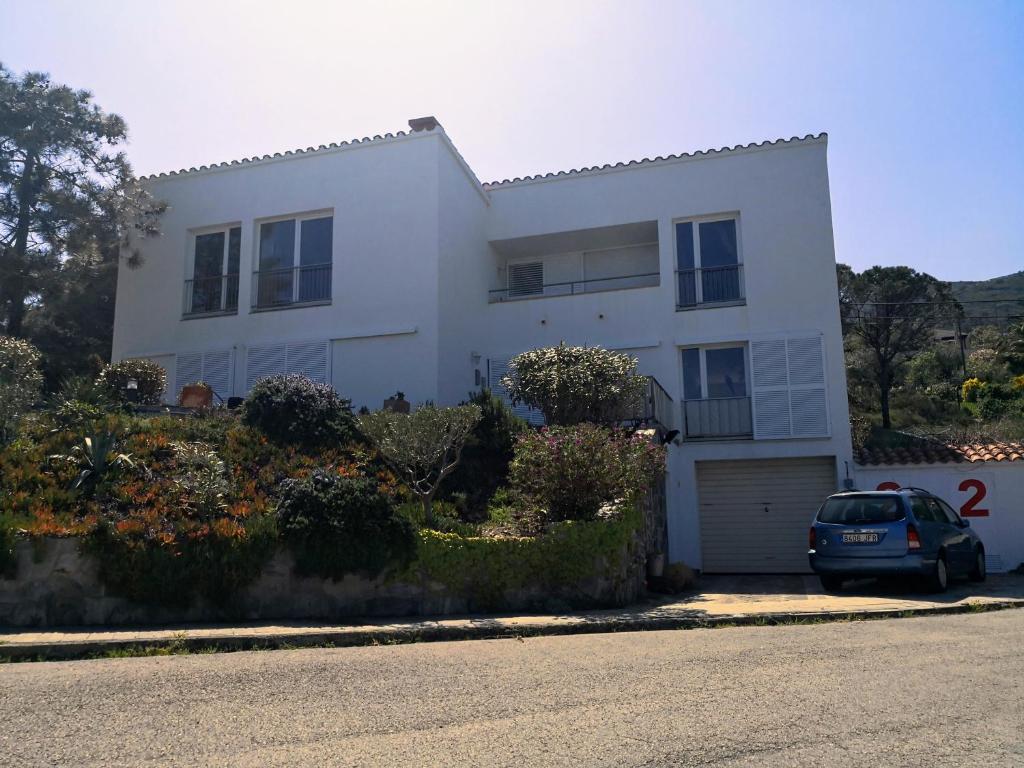 a white house with a car parked in front of it at La Vista in Port de la Selva