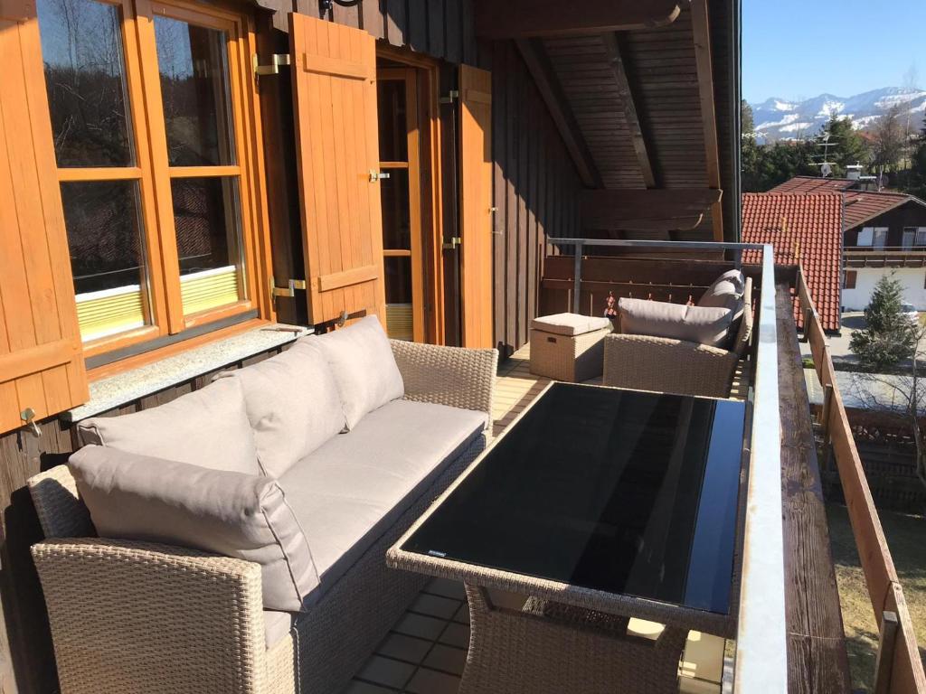 een patio met een bank en een tafel op een balkon bij FeWo "Sonnenschein" Oberreute in Oberreute