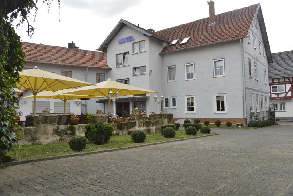 a hotel with tables and umbrellas in front of it at Hotel Zur Stadt Cassel in Neukirchen