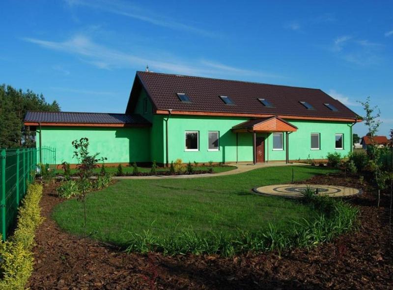 uma casa verde com um telhado preto e um quintal em Pokoje Pod Lasem em Stepnica