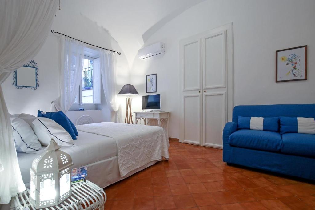 a bedroom with a bed and a blue couch at Vicolo 23 1 Minutes to Beach and Square Atrani in Atrani